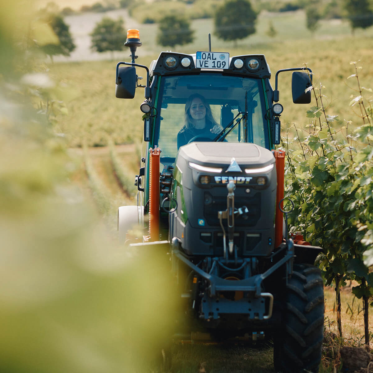 Juliane Eller, Gründerin von JUWEL Weine, fährt den grünen Fendt e107 V Vario Traktor durch die Weinberge in Alsheim