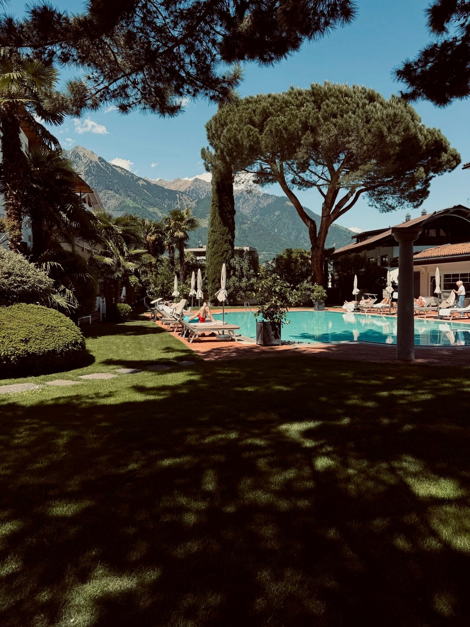 Pool beim Romantik Hotel Oberwirt, umgeben von Bäumen und Bergen